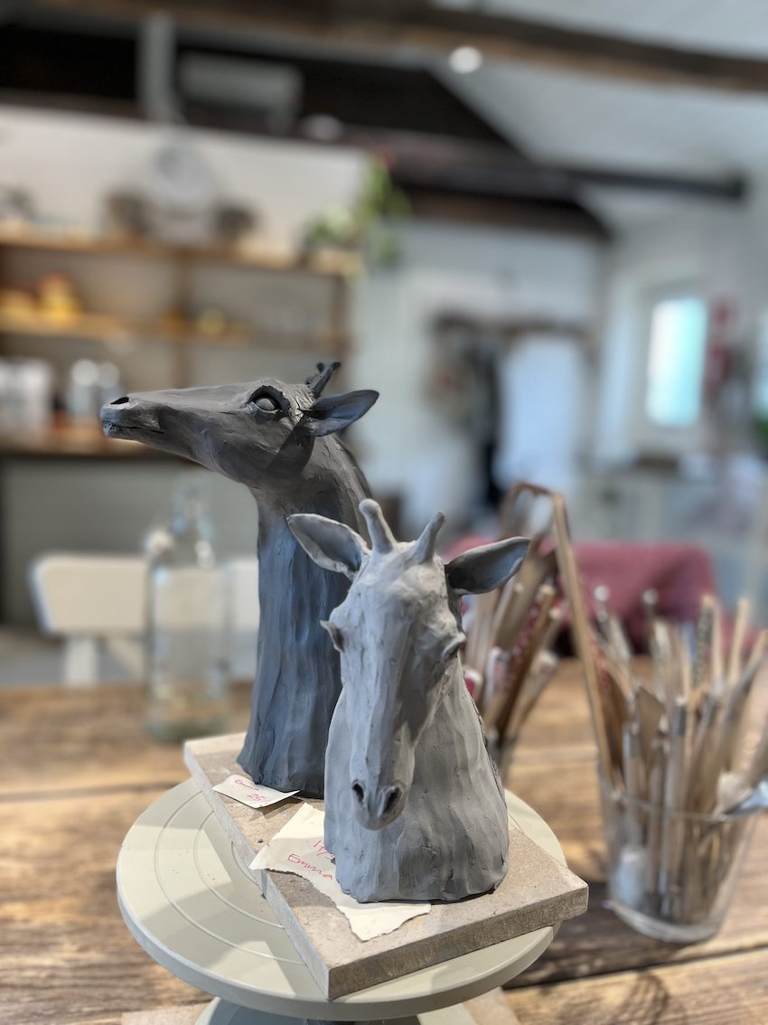 Två giraffskulpturer i keramikverkstaden med verktyg runt omkring